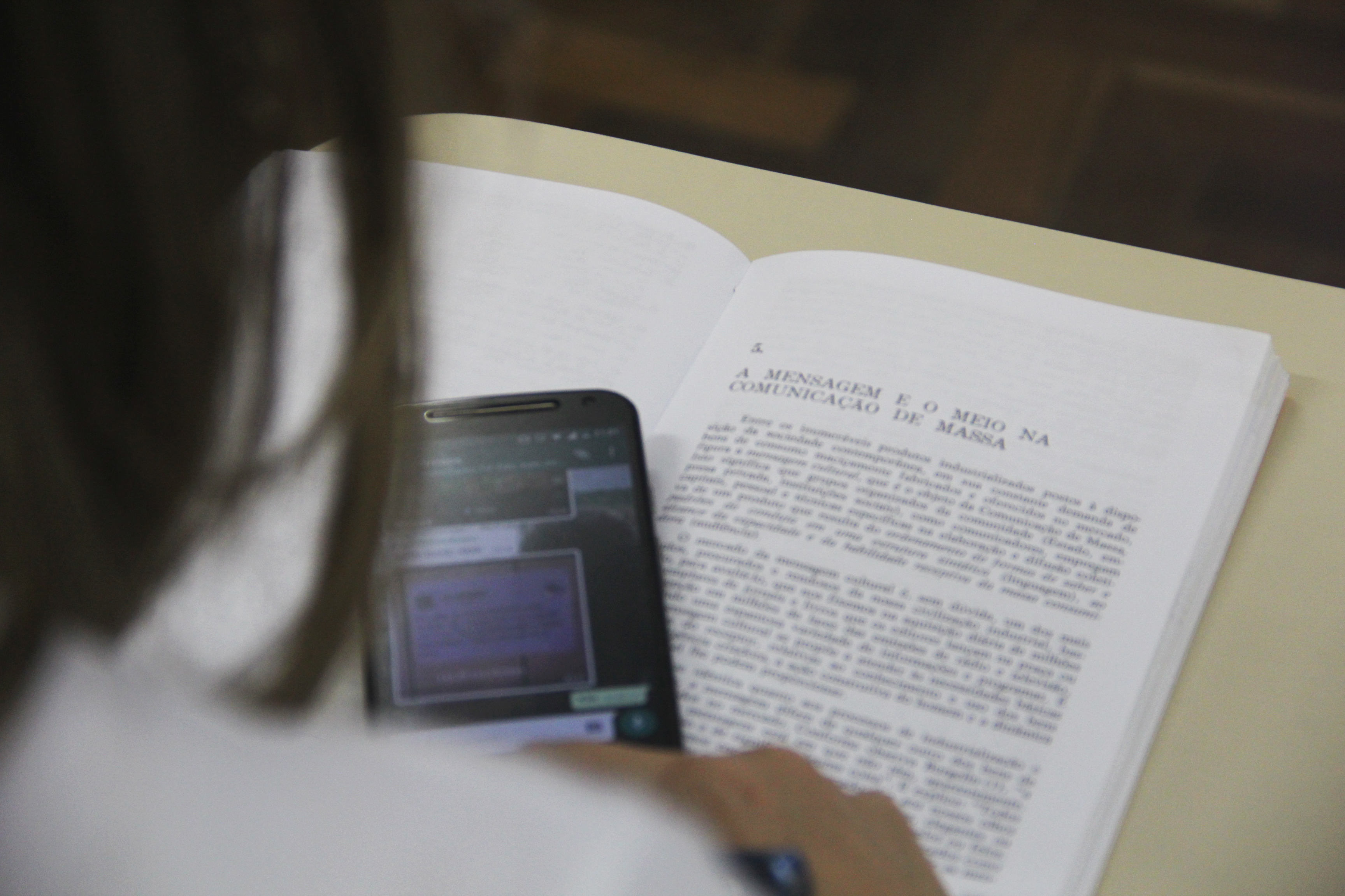 Pessoa usando celular em cima do livro